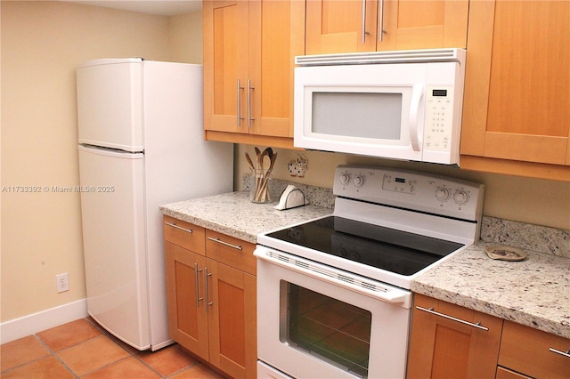 kitchen featuring light stone counters, white appliances, and light tile patterned floors