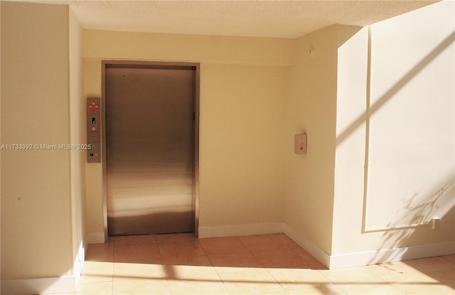 hallway with elevator and light tile patterned floors