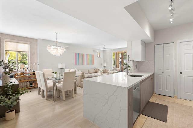 kitchen with sink, dishwasher, light hardwood / wood-style floors, decorative light fixtures, and kitchen peninsula