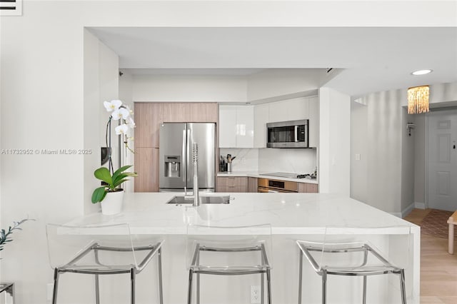 kitchen with light stone countertops, white cabinetry, appliances with stainless steel finishes, and kitchen peninsula