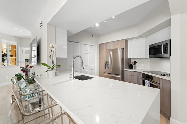 kitchen featuring sink, white cabinetry, stainless steel appliances, a kitchen bar, and kitchen peninsula