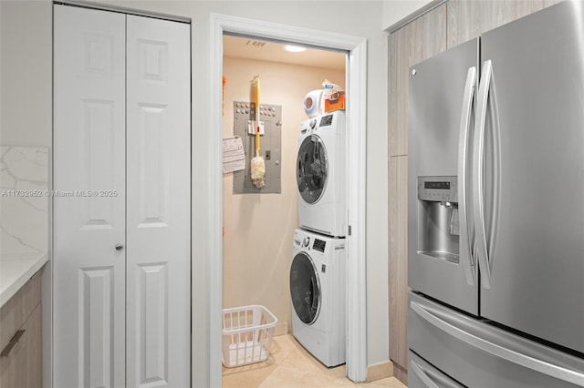 clothes washing area featuring stacked washer and dryer and light tile patterned flooring