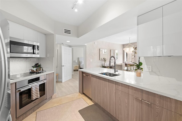 kitchen featuring pendant lighting, sink, light tile patterned floors, appliances with stainless steel finishes, and white cabinetry