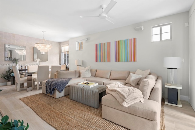 living room with ceiling fan with notable chandelier and light wood-type flooring