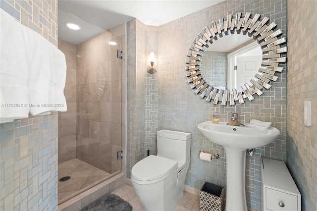 bathroom featuring a shower with shower door, tile walls, decorative backsplash, toilet, and tile patterned floors