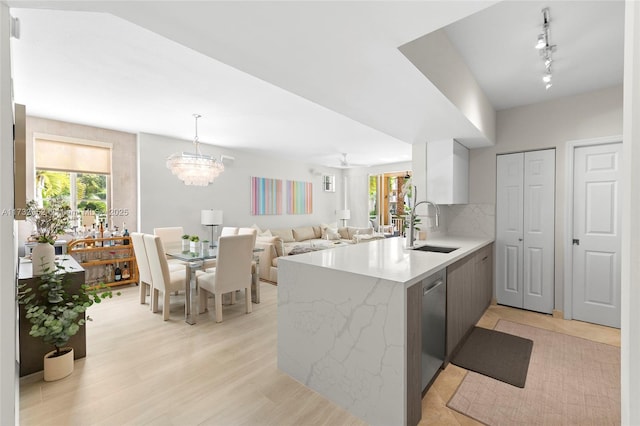 kitchen with sink, white cabinets, hanging light fixtures, stainless steel dishwasher, and kitchen peninsula