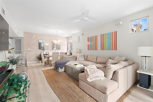 living room with ceiling fan with notable chandelier and light wood-type flooring