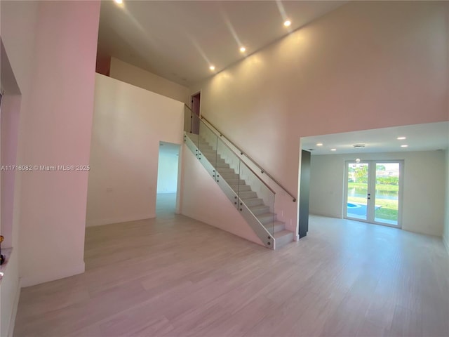 staircase with a high ceiling, wood-type flooring, and french doors