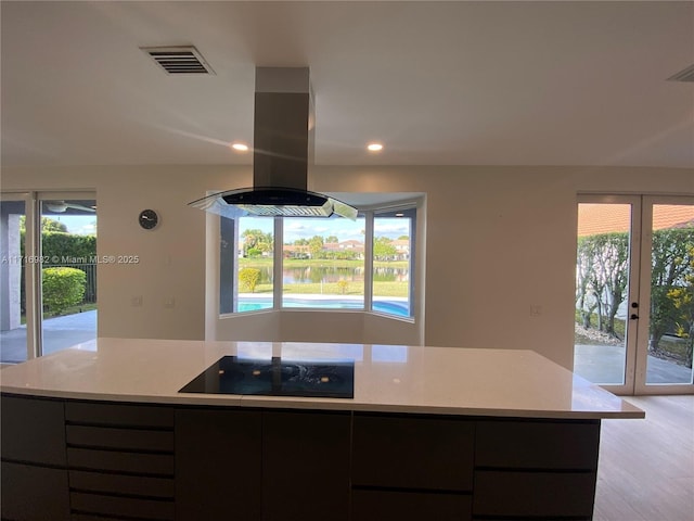 kitchen with black electric stovetop, light wood-type flooring, french doors, and island exhaust hood