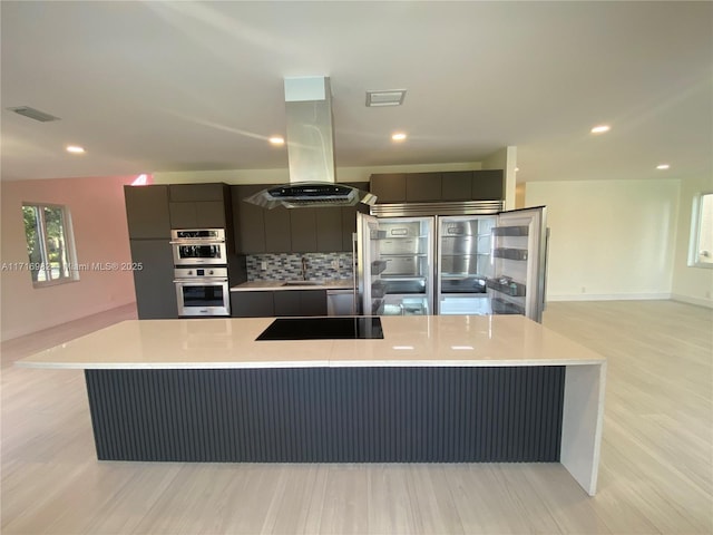 kitchen featuring sink, island exhaust hood, stainless steel appliances, a large island, and light hardwood / wood-style floors