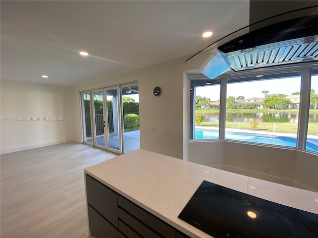 kitchen featuring black stovetop, a healthy amount of sunlight, and a water view