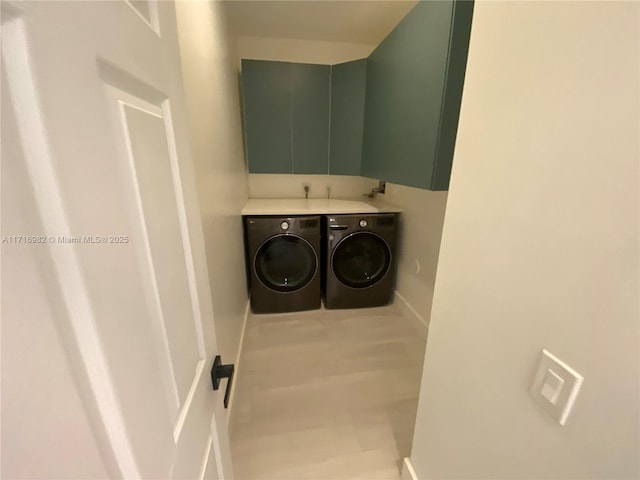 clothes washing area with cabinets and washing machine and clothes dryer