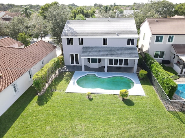 back of house with a fenced in pool and a lawn