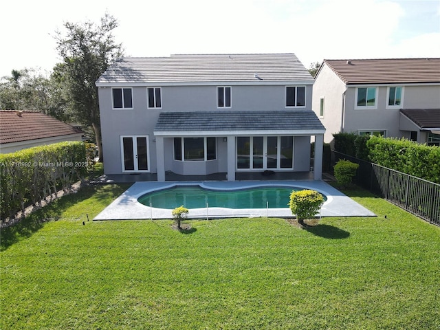 back of property with a fenced in pool, a patio area, and a lawn