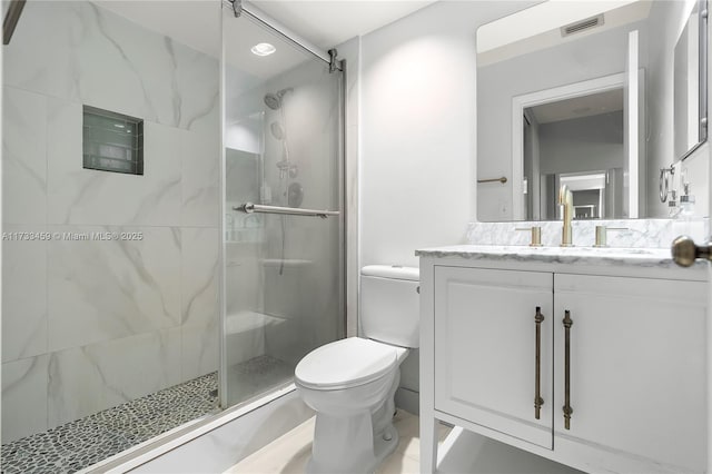 bathroom featuring vanity, toilet, and a shower with shower door