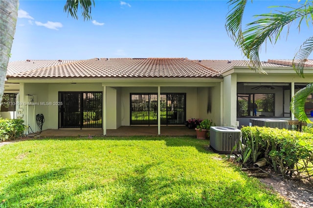 back of property with ceiling fan, a yard, and central air condition unit