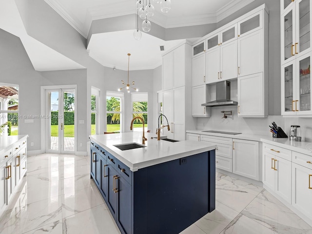 kitchen with pendant lighting, sink, wall chimney range hood, and a kitchen island with sink