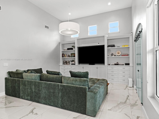 living room with built in shelves and a high ceiling