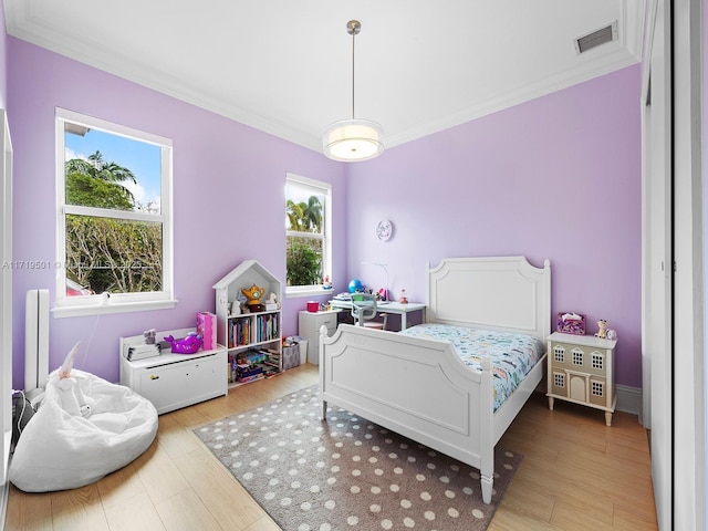 bedroom featuring ornamental molding and light hardwood / wood-style floors