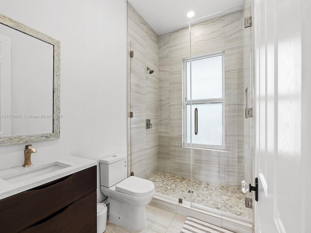 bathroom with vanity, a shower with shower door, tile patterned floors, and toilet