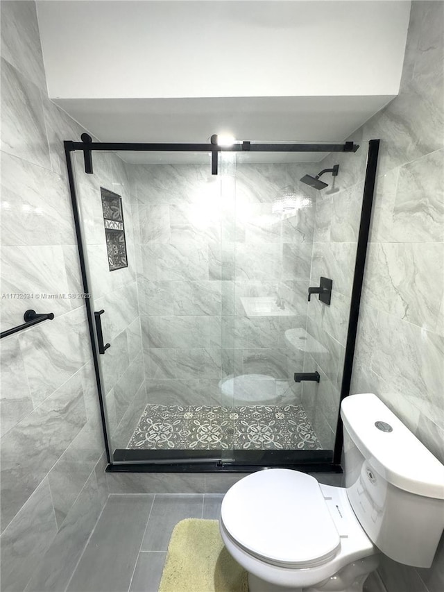 bathroom featuring a shower with door, tile patterned flooring, and toilet