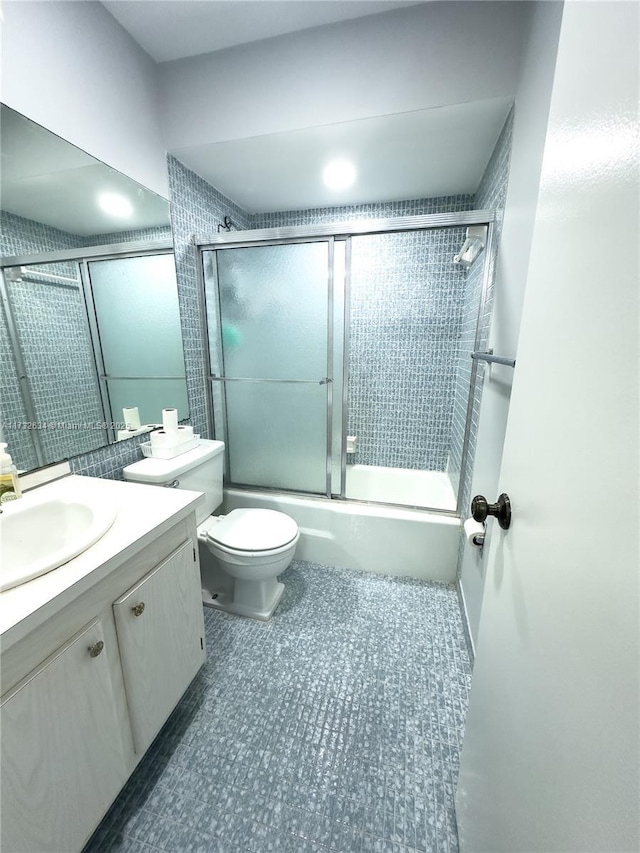 full bathroom featuring enclosed tub / shower combo, vanity, and toilet