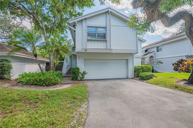 36 Eastmont Rd, Hollywood, FL 33021 - view of front facade with a garage, asphalt driveway, board and batten siding, and a front lawn