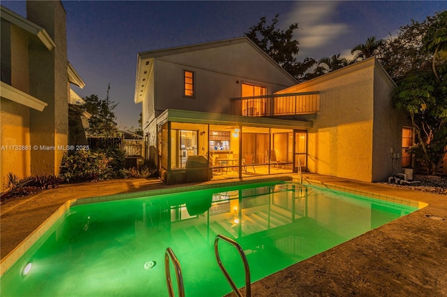 36 Eastmont Rd, Hollywood, FL 33021 - back of house at twilight with a balcony, an outdoor pool, a patio area, and stucco siding
