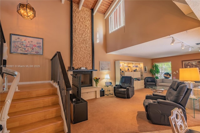 carpeted living room featuring high vaulted ceiling, wood ceiling, stairs, beamed ceiling, and track lighting