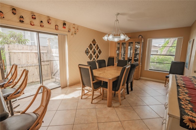 dining space with light tile patterned floors, a textured ceiling, and an inviting chandelier