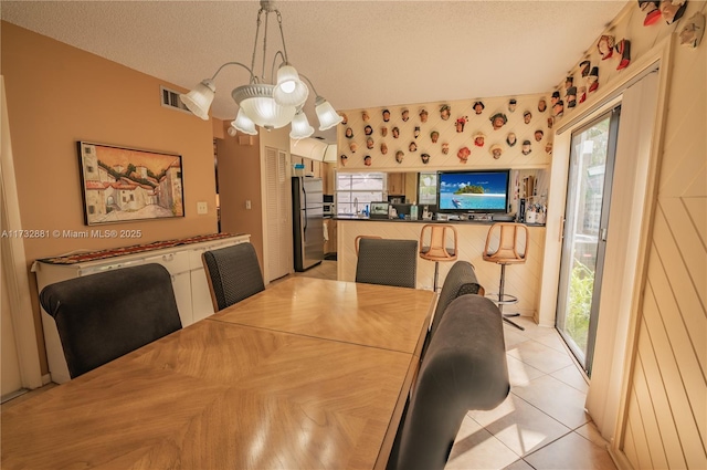 dining room with visible vents, a textured ceiling, and light tile patterned flooring