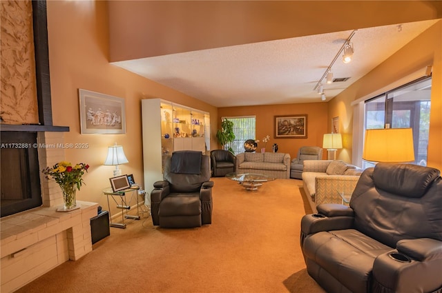 living room with carpet floors, rail lighting, visible vents, a large fireplace, and a textured ceiling