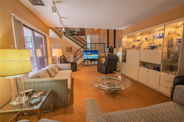 carpeted living room with track lighting, visible vents, stairway, and a textured ceiling