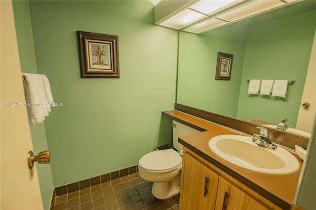 half bath with baseboards, vanity, toilet, and tile patterned floors