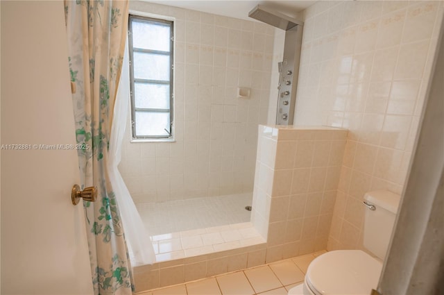 full bathroom featuring tile patterned flooring, tiled shower, tile walls, and toilet