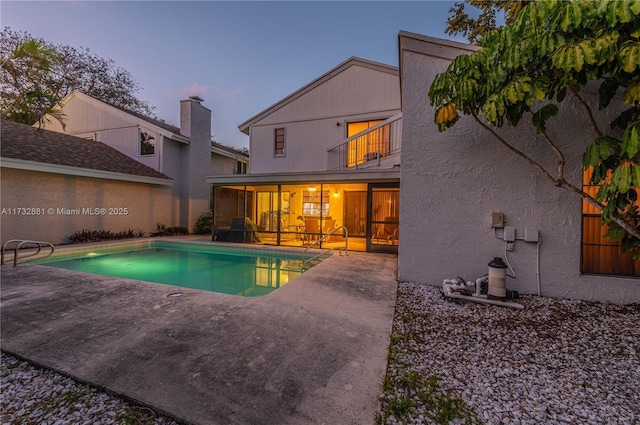 pool at dusk featuring a fenced in pool, a sunroom, and a patio