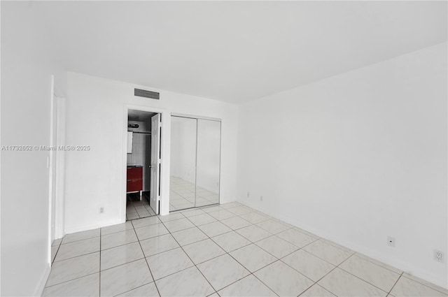 unfurnished bedroom featuring light tile patterned floors, ensuite bath, and a closet