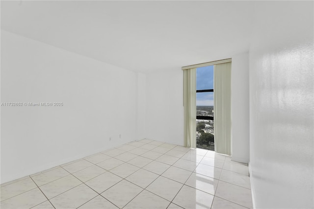 tiled empty room featuring floor to ceiling windows