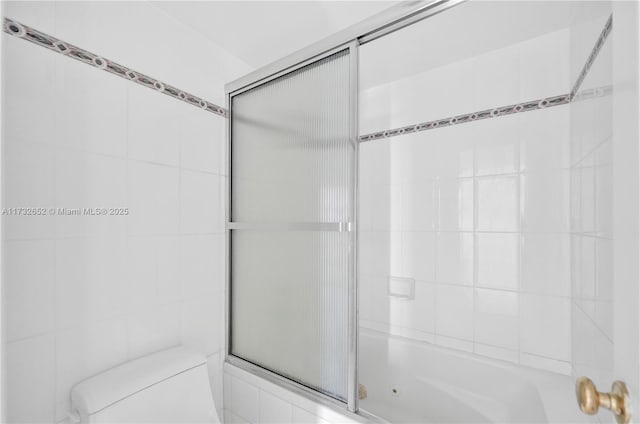 bathroom featuring toilet and shower / bath combination with glass door