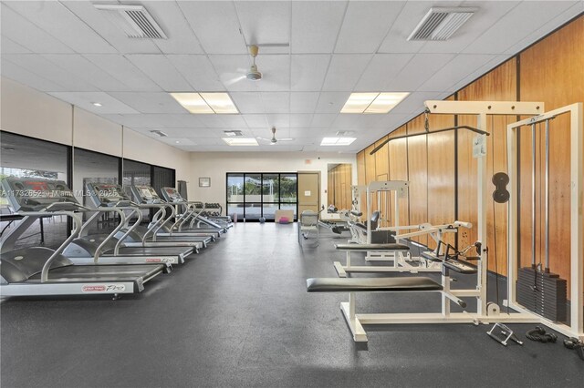 gym featuring a paneled ceiling and wooden walls