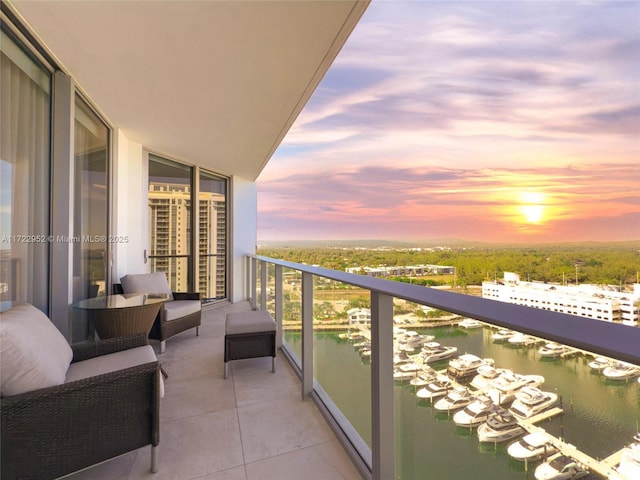 balcony at dusk featuring a water view