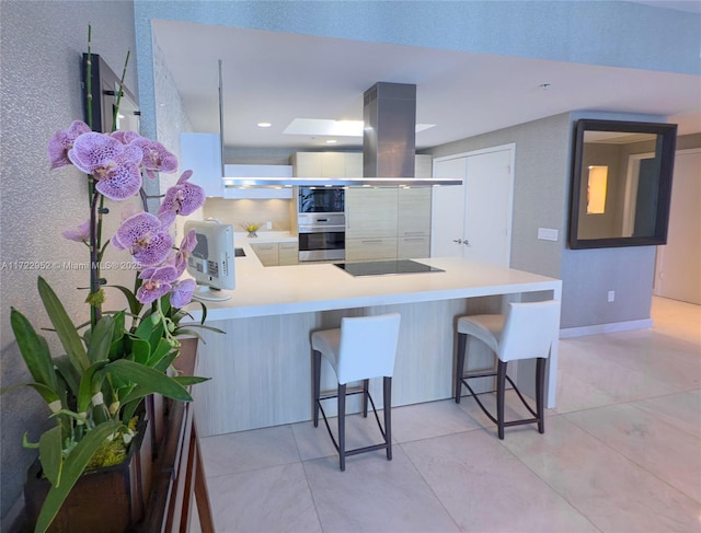 17111 Biscayne Blvd Unit 1705, North Miami Beach, FL 33160 - kitchen with stainless steel oven, built in microwave, a breakfast bar area, black electric cooktop, and a peninsula