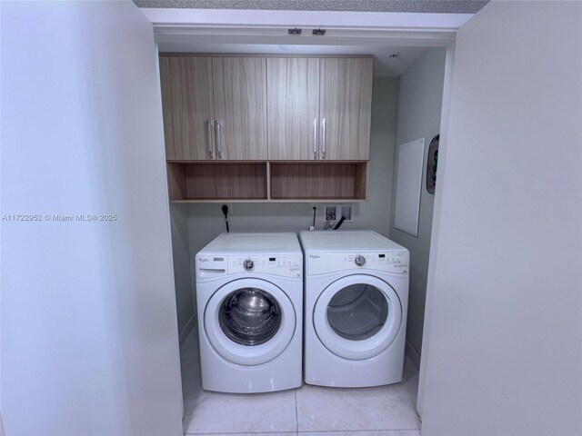 laundry room featuring light tile patterned floors, cabinets, and washing machine and clothes dryer