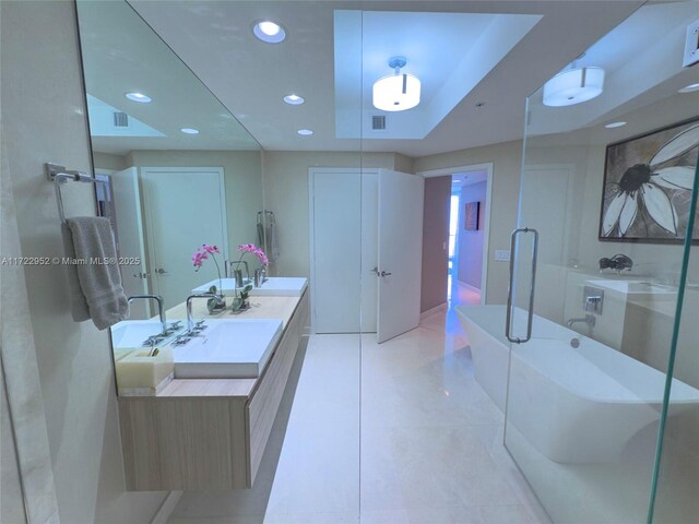 bathroom with vanity, a tub, and a tray ceiling