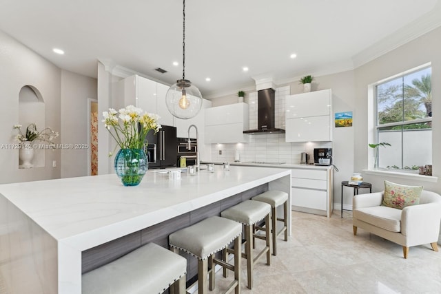 kitchen featuring wall chimney exhaust hood, modern cabinets, white cabinetry, and tasteful backsplash