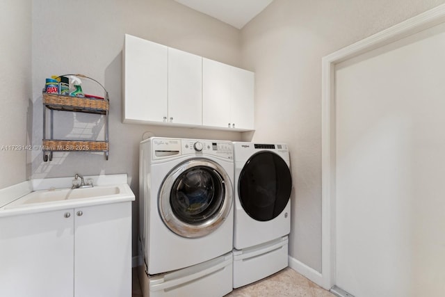 washroom with washing machine and dryer, cabinet space, a sink, and baseboards