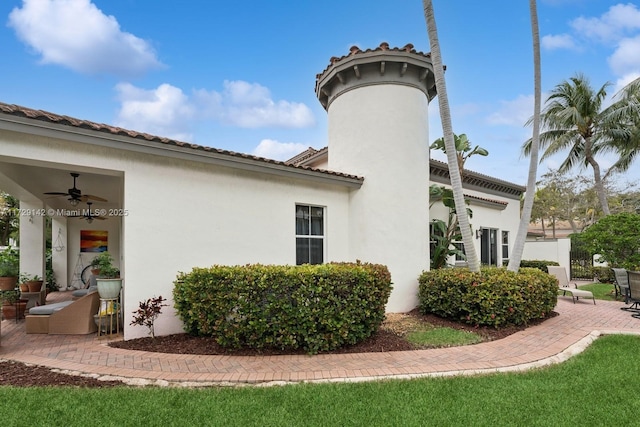 view of side of property with a patio, a tile roof, and stucco siding