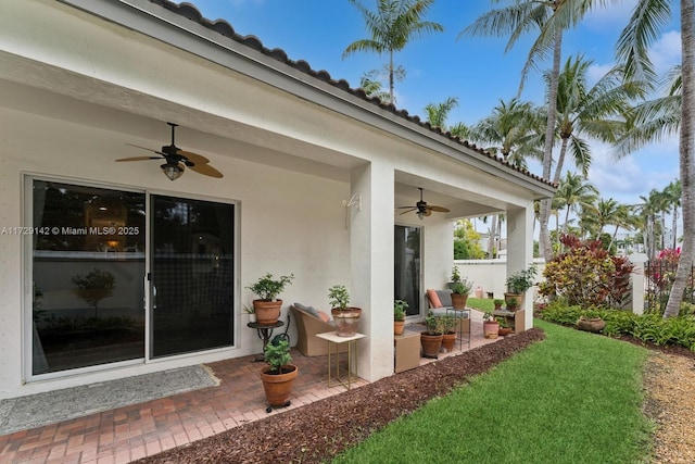 exterior space with a yard, a patio, stucco siding, a ceiling fan, and fence