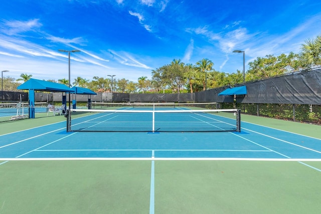 view of tennis court featuring community basketball court and fence