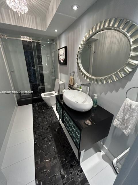 bathroom featuring a notable chandelier, walk in shower, vanity, and toilet